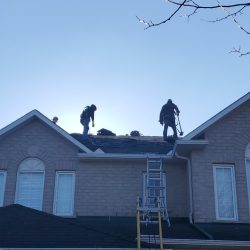 Silhouettes of roofers standing on a roof while working Silhouettes of roofers standing on a roof while working